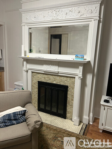 A white fireplace with a mirror above it and a couch in front of it.