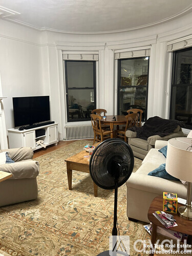 A living room with a fan, couch, and television.