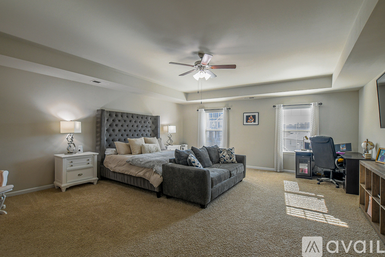 A bedroom with a large bed and a grey couch.