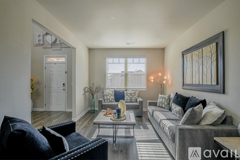A living room with a grey couch, a coffee table, and a painting on the wall.