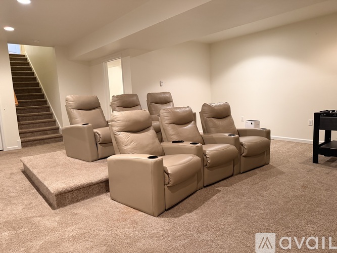 A living room with a row of recliner chairs and a staircase in the background.
