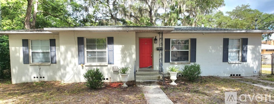 A white house with a red door and black shutters.