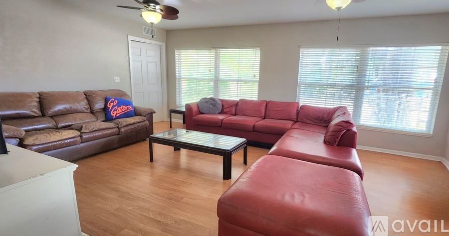 A living room with a brown leather couch and a red leather couch.