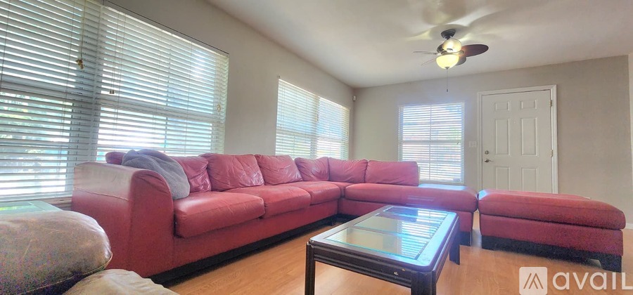 A living room with a red couch and a glass coffee table.