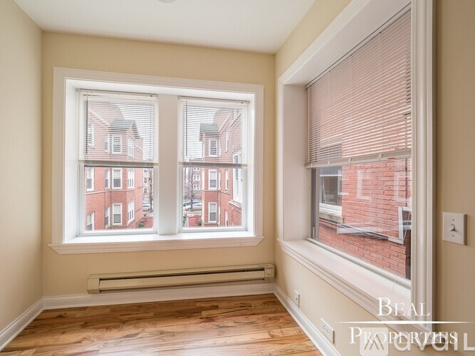A room with a large window showing a view of a red brick building.