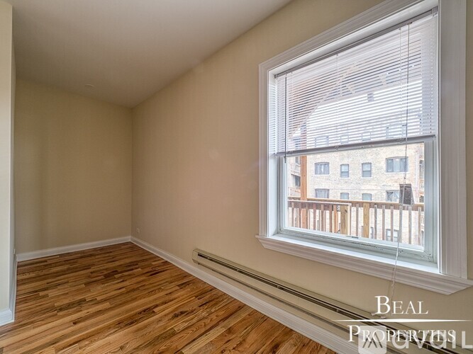 A room with wooden floors and a large window overlooking a balcony.
