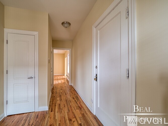 A hallway with wood floors and white doors.