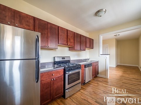A kitchen with wooden cabinets and a stainless steel refrigerator.