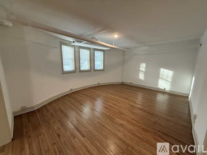 A room with wooden flooring and white walls.