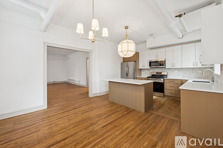 A spacious room with wooden flooring and white walls.