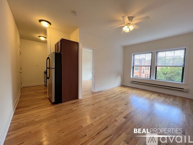 A spacious room with wooden flooring and a large window.