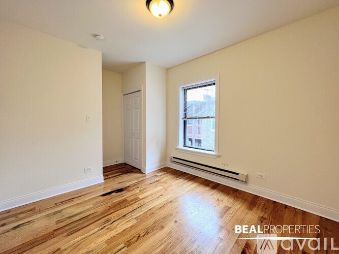 A room with wooden floors and a window with a view of a building outside.