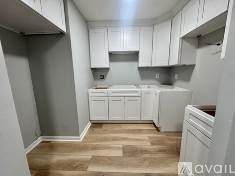 A kitchen with white cabinets and a wooden floor.