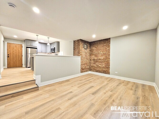 A spacious room with wooden flooring and a brick wall.
