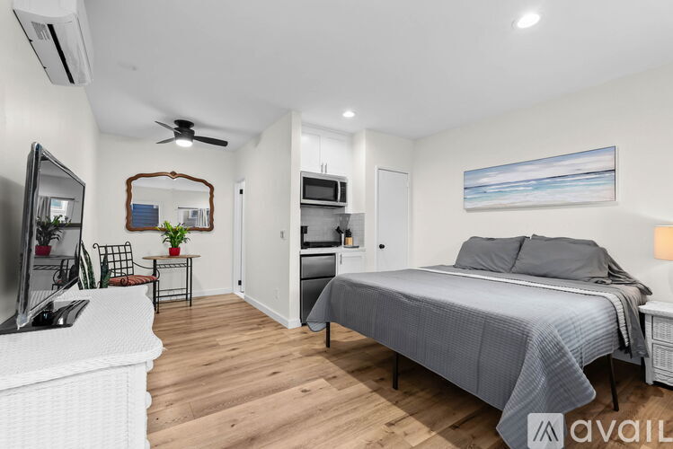 A bedroom with a bed, a television, and a mirror.