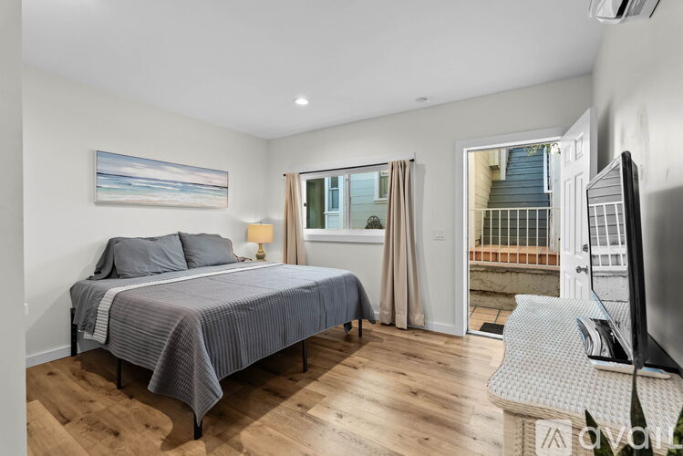 A bedroom with a bed, a television, and a window with curtains.
