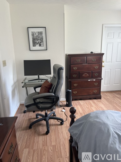 A black monitor sits on a desk with a chair in front of it.