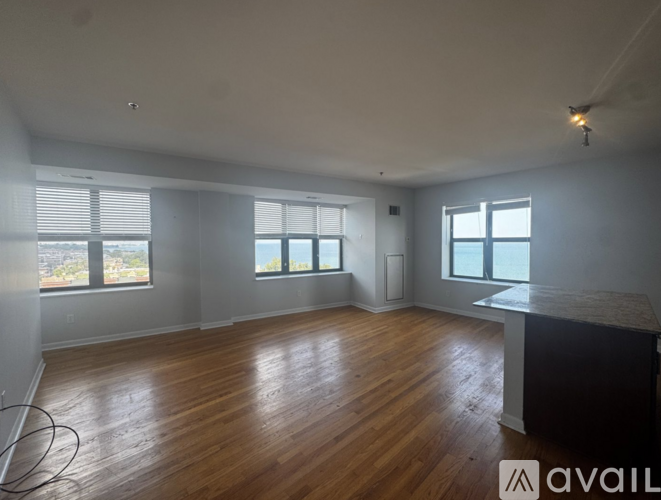A spacious room with wooden floors and large windows.