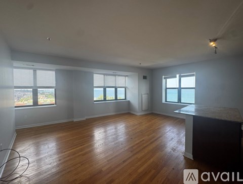 A spacious room with wooden floors and large windows.