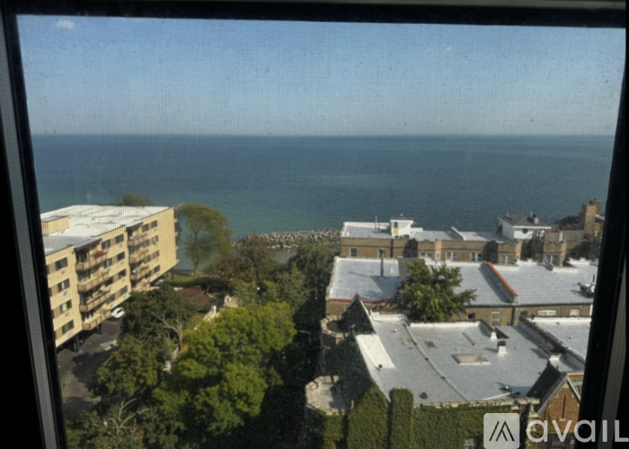 A view of a residential area with apartment buildings and a body of water in the distance.