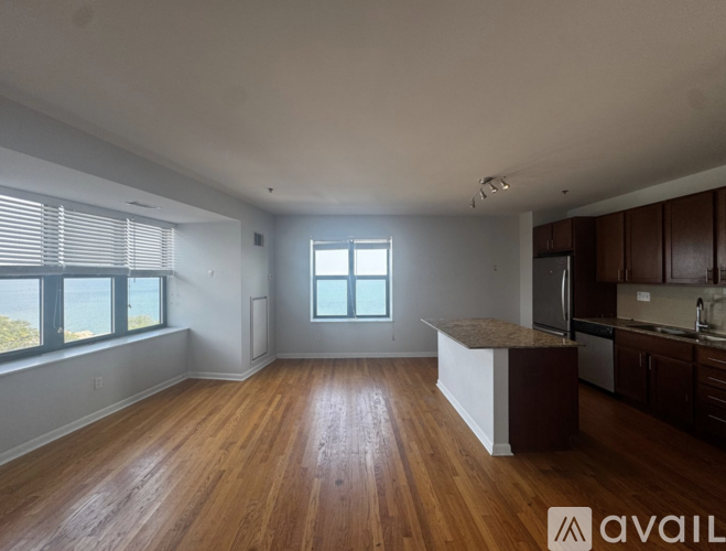 A spacious kitchen and living room with wooden floors and large windows.