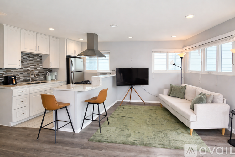 A modern kitchen with a bar stool and a couch.