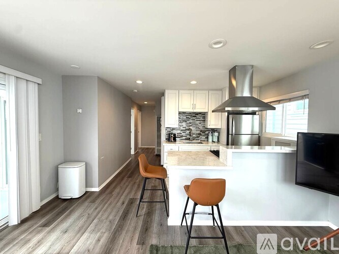 A modern kitchen with a bar stool and a TV.
