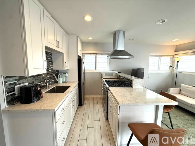 A kitchen with white cabinets and a marble countertop.