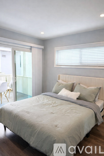 A bedroom with a large bed and a sliding glass door.