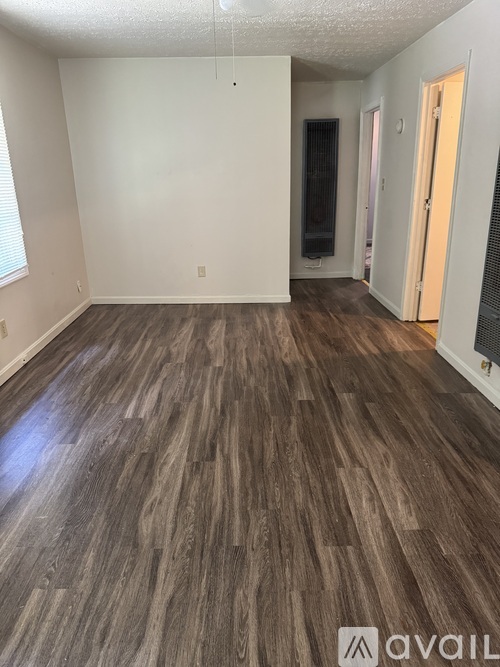 A room with wooden flooring and white walls.