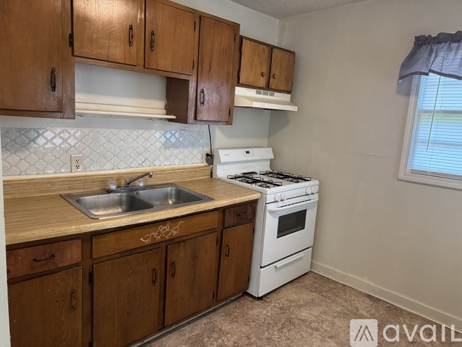 A kitchen with wooden cabinets and a white stove top oven.