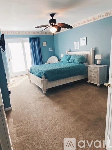 A bedroom with a bed, nightstand, and a ceiling fan.