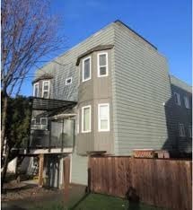 A house with a grey siding and a brown fence.