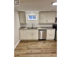 A kitchen with white cabinets and a wooden floor.
