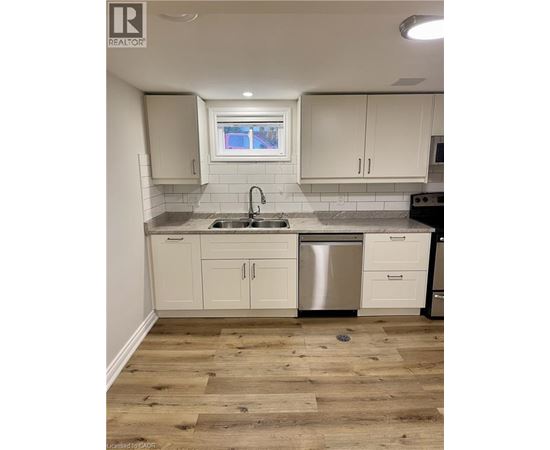 A kitchen with white cabinets and a wooden floor.