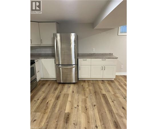 A kitchen with a stainless steel refrigerator and wooden floors.