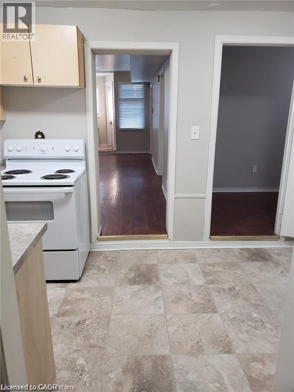 A kitchen with a white stove top oven and a tiled floor.