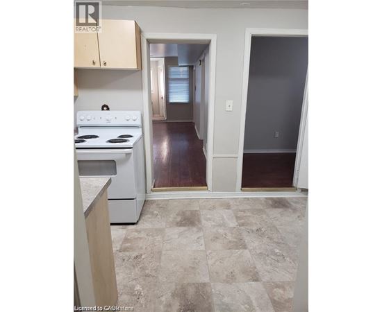 A kitchen with a white stove top oven and a tiled floor.