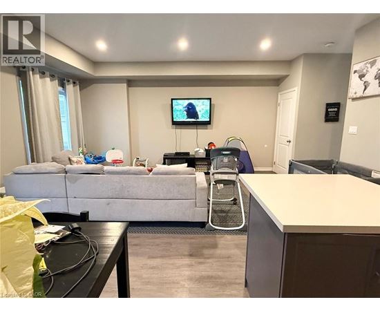 A living room with a grey sofa and a television on the wall.