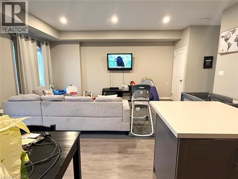 A living room with a grey sofa and a television on the wall.