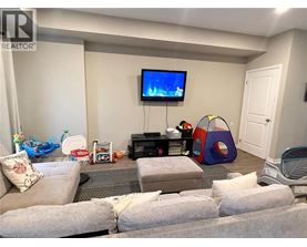 A living room with a grey couch, a television, a gaming console, and a bean bag chair.