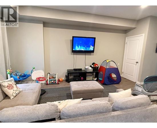 A living room with a grey couch, a television, a gaming console, and a bean bag chair.