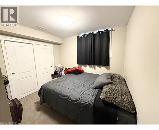 A bedroom with a bed, pillow, and a suitcase.
