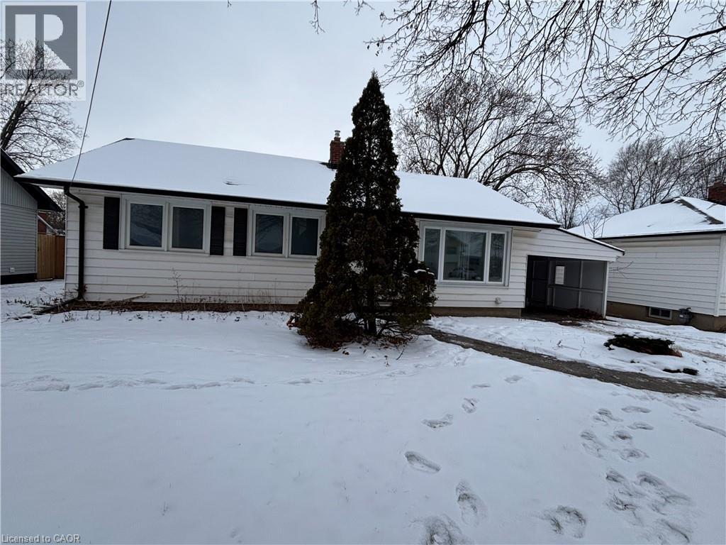 A house with a snow-covered ground and a tree in front.