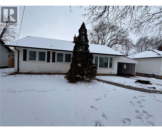 A house with a snow-covered ground and a tree in front.