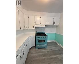 A kitchen with a blue stove and white cabinets.