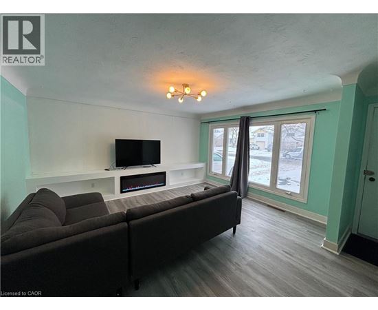 A living room with a grey couch and a television on a white stand.
