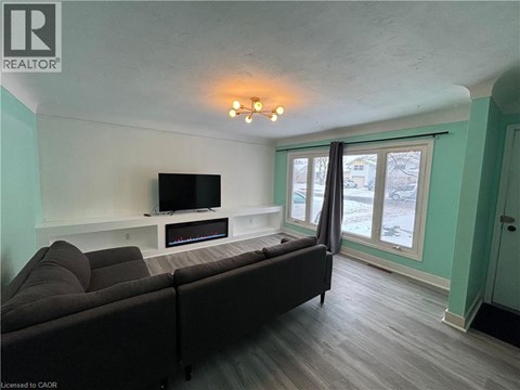 A living room with a grey couch and a television on a white stand.