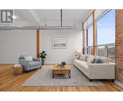 A living room with a blue couch, a grey rug, a wooden coffee table, and a painting on the wall.