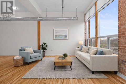A living room with a blue couch, a grey rug, a wooden coffee table, and a painting on the wall.
